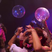 Public, adultes et enfants les bras en l'air dans une salle de spectacle