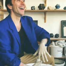 Thomas Poitevin sourit assis devant un tour de poterie qu'il modèle
