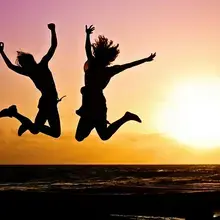 Deux personnes dansant et sautant librement au coucher du soleil, symbole de joie et de liberté 