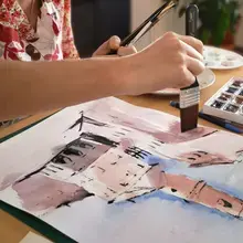 Atelier d’aquarelle : une participante réalise un carnet de voyage avec des techniques artistiques.