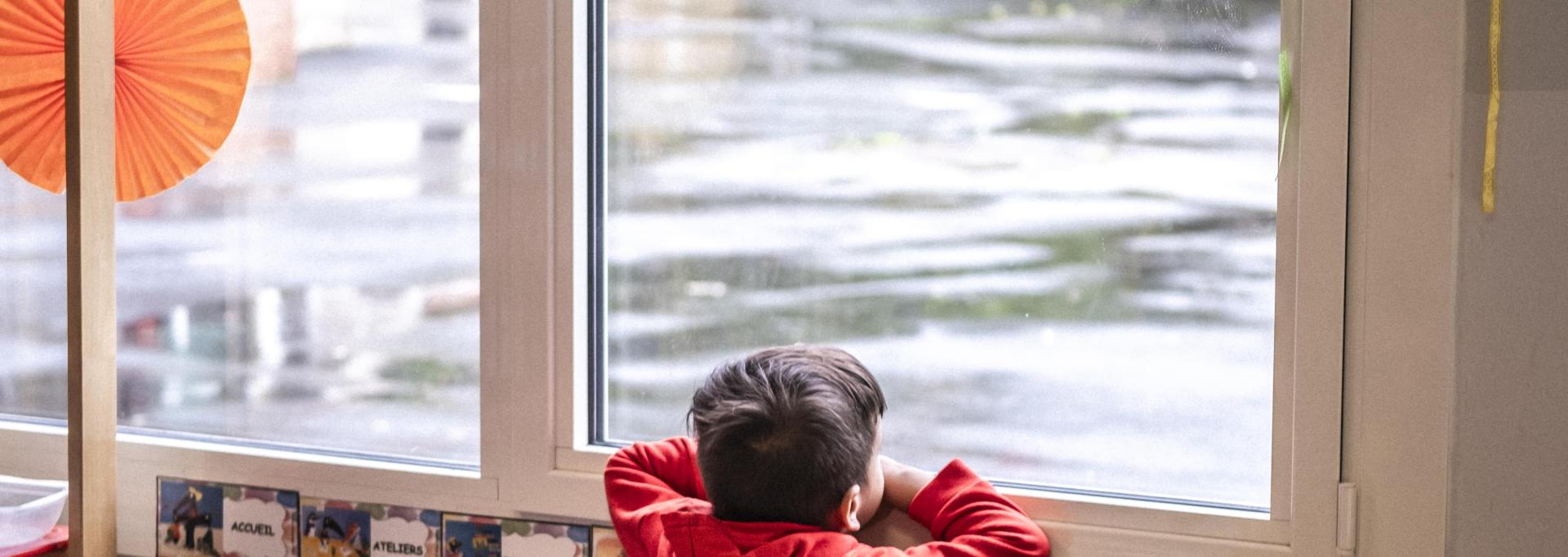 Un enfant tout seul à une fenetre