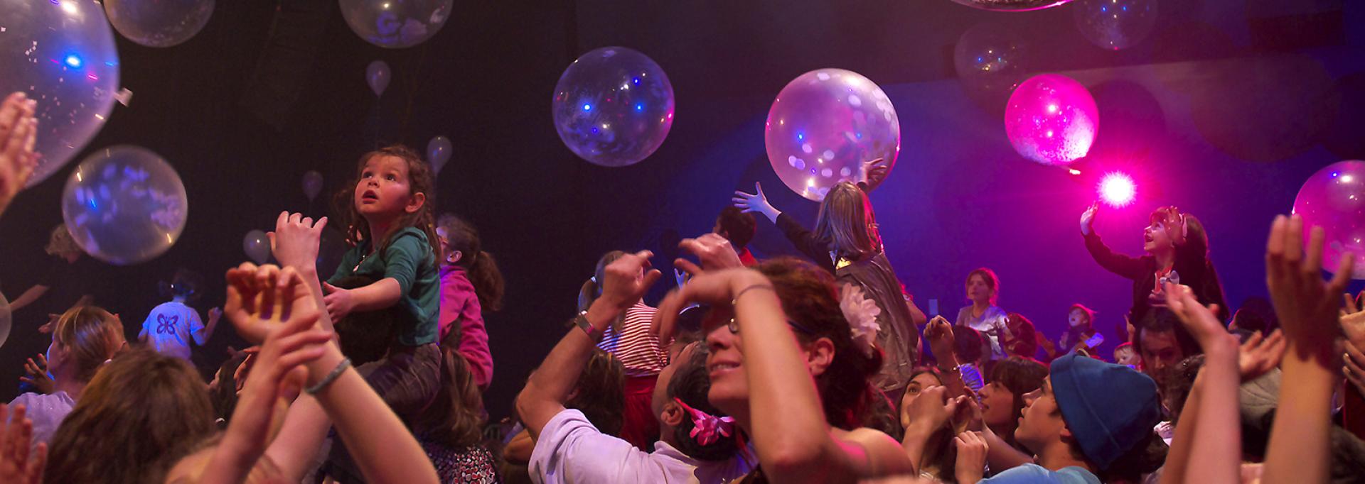 Public, adultes et enfants les bras en l'air dans une salle de spectacle