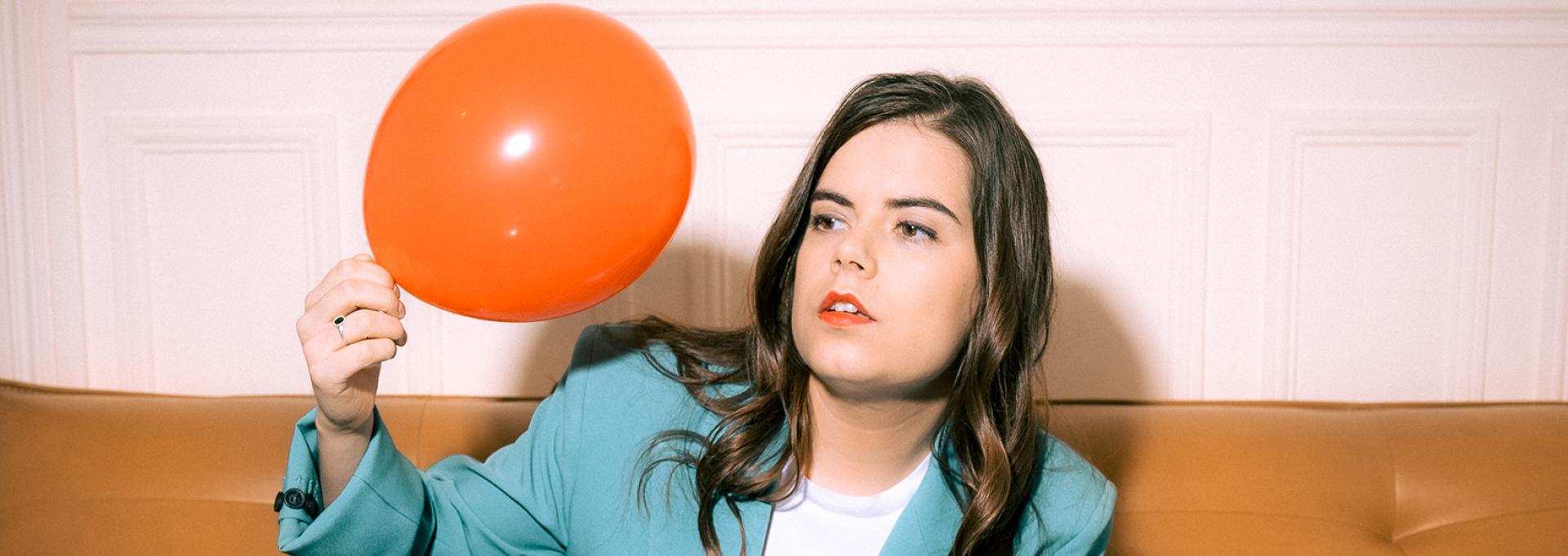 Fanny Ruwet sur un canapé regardant un ballon de baudruche