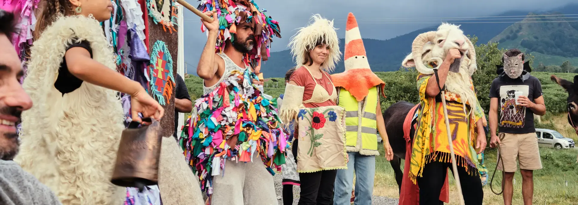 Un groupe d'adultes et d'enfants avec costumes de laine et sonnailles effectuent une transhumance artistique en Vallée d'Aspe.