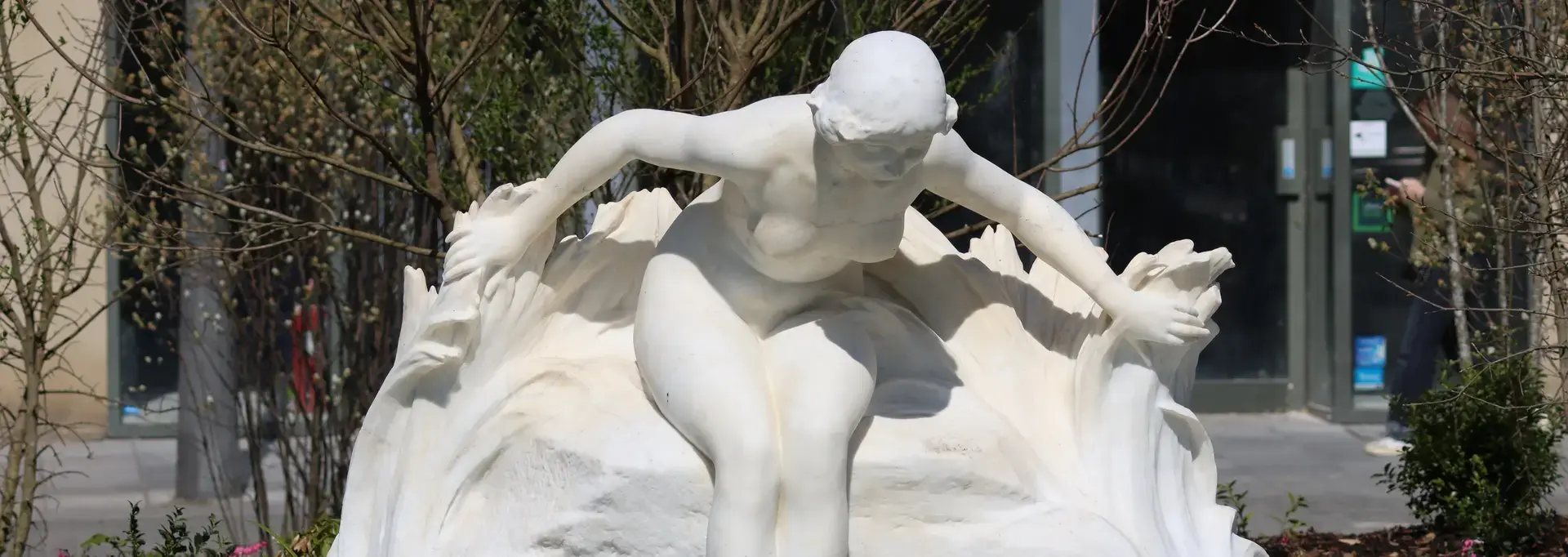 Statue blanche d'une baigneuse déposant délicatement les pieds à la surface du nouveau bassin place Clémenceau
