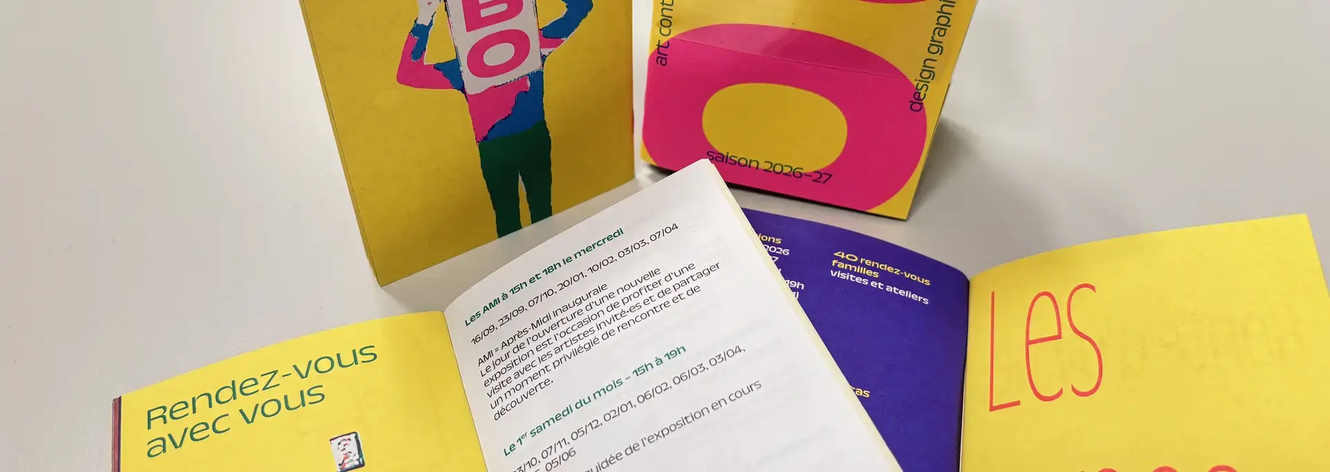 Mise en scène de plusieurs programmes de saison montrant la une et la dernière de couverture et des pages intérieures. Pour la saison 2026-2027, ce document adopte un mini format coloré, facile à emporter avec soi. 