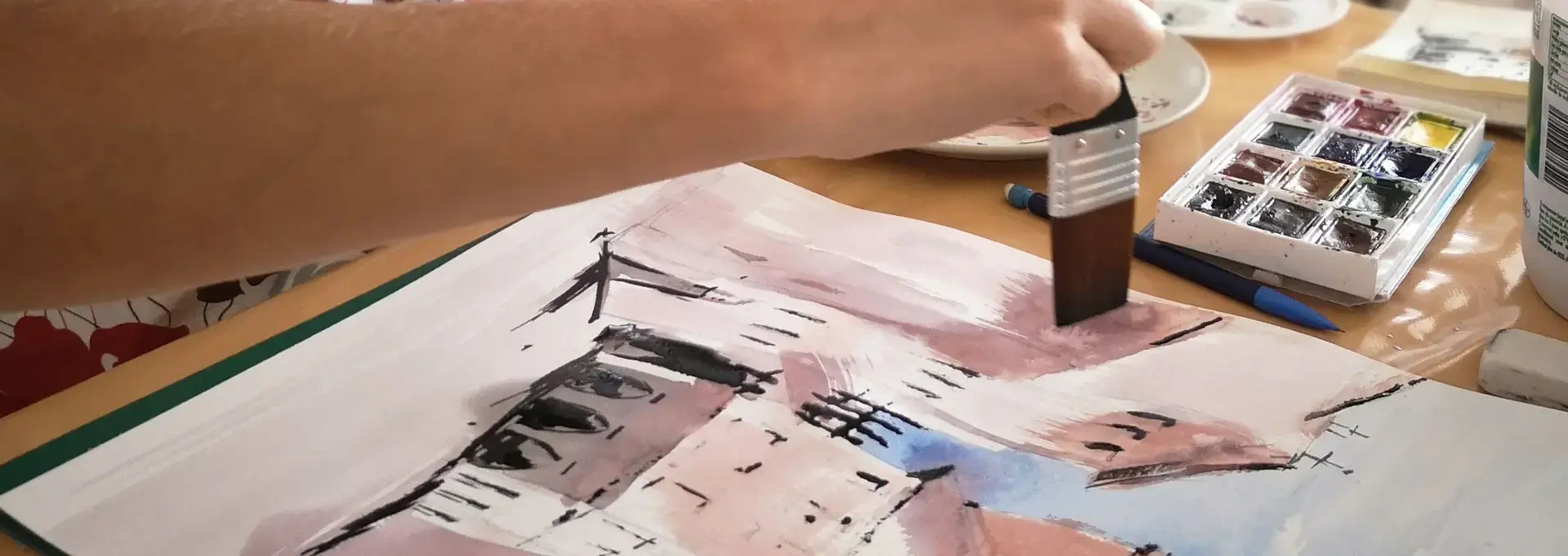 Atelier d’aquarelle : une participante réalise un carnet de voyage avec des techniques artistiques.