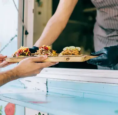 Propriétaire d'un foodtruck servant des tacos à un client