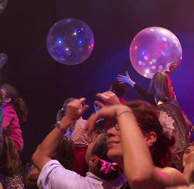 Public, adultes et enfants les bras en l'air dans une salle de spectacle