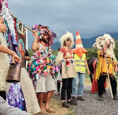 Un groupe d'adultes et d'enfants avec costumes de laine et sonnailles effectuent une transhumance artistique en Vallée d'Aspe.