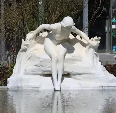 Statue blanche d'une baigneuse déposant délicatement les pieds à la surface du nouveau bassin place Clémenceau