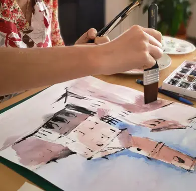 Atelier d’aquarelle : une participante réalise un carnet de voyage avec des techniques artistiques.