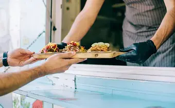 Propriétaire d'un foodtruck servant des tacos à un client