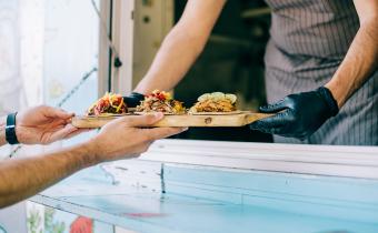 Propriétaire d'un foodtruck servant des tacos à un client