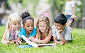 Des enfants en train de lire en extérieur
